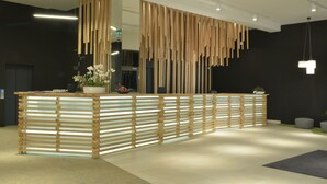A reception desk with a modern design, featuring a slatted wooden structure and a mirrored surface. - Focus Hotel Premium Lublin Conference & SPA (gmina Jastków)