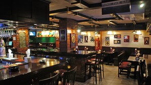 A bar area with wooden bar counters, chairs, and a variety of bottles and glasses. - Comfort Hotel Suites (Amman)