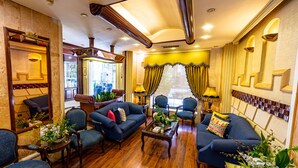 A spacious living room with a blue sofa set, wooden coffee table, and multiple chairs. - Comfort Hotel Suites (Amman)