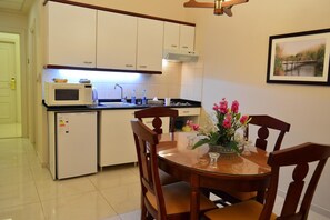 A compact kitchen with a microwave, sink, and a dining area with a table and chairs. - Comfort Hotel Suites (Amman)