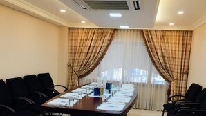 A conference room with a long table, black chairs, and a projector. - Comfort Hotel Suites (Amman)