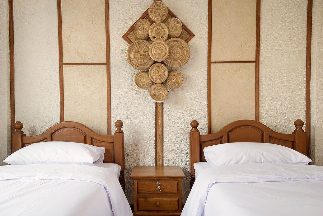 A double bed with a wooden headboard, a nightstand with a drawer, and a wall-mounted decorative item.