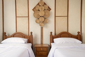 A double bed with a wooden headboard, a nightstand with a drawer, and a wall-mounted decorative item. - Sailomjoy, The Boutique Hostel (Mae Sai)