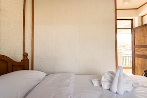 A hotel room with a wooden headboard, a patterned wall, and a view of the outside balcony. - Sailomjoy, The Boutique Hostel (Mae Sai)