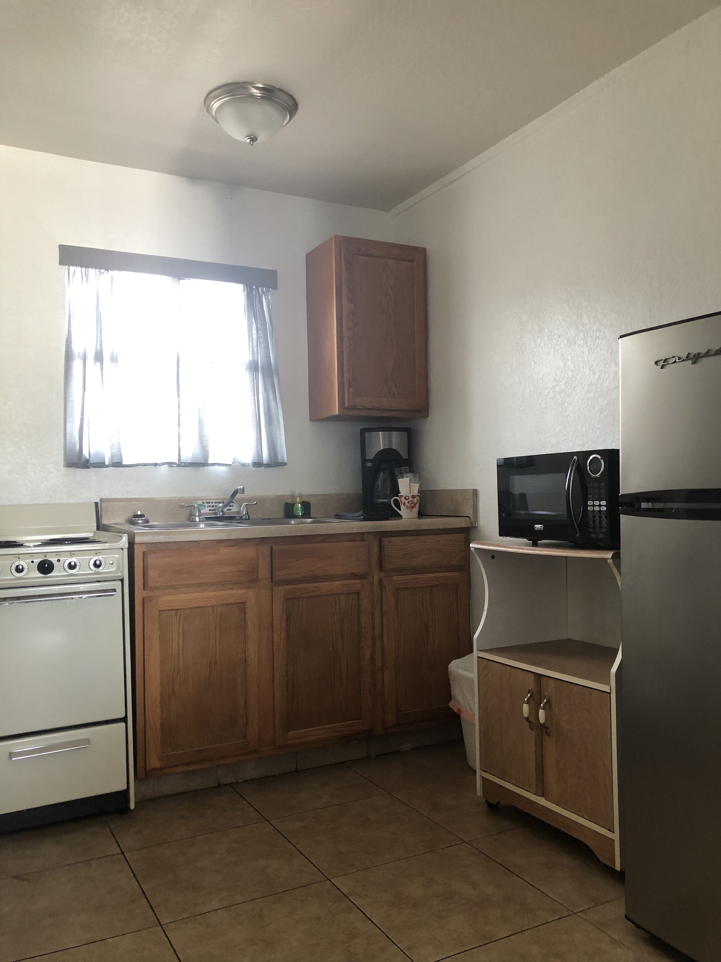 Una cocina con armarios de madera, estufa blanca, microondas y refrigerador.
