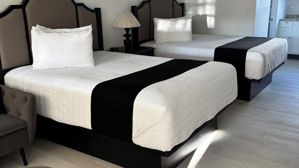 A hotel room with two beds, a desk, and a chair. - Holiday Isles Resort (Madeira Beach)