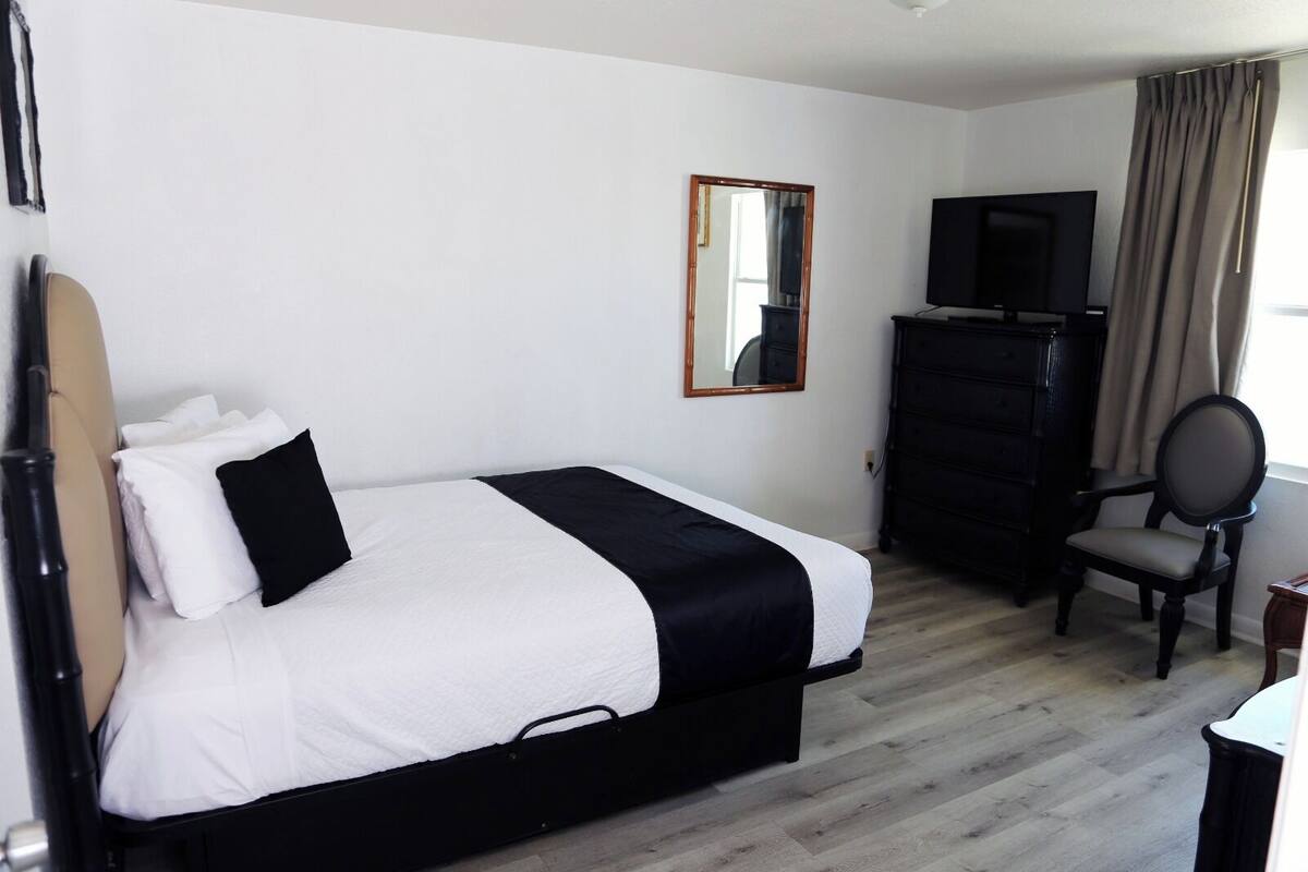 Ett hotellrum med en säng, en byrå, en tv och en stol.