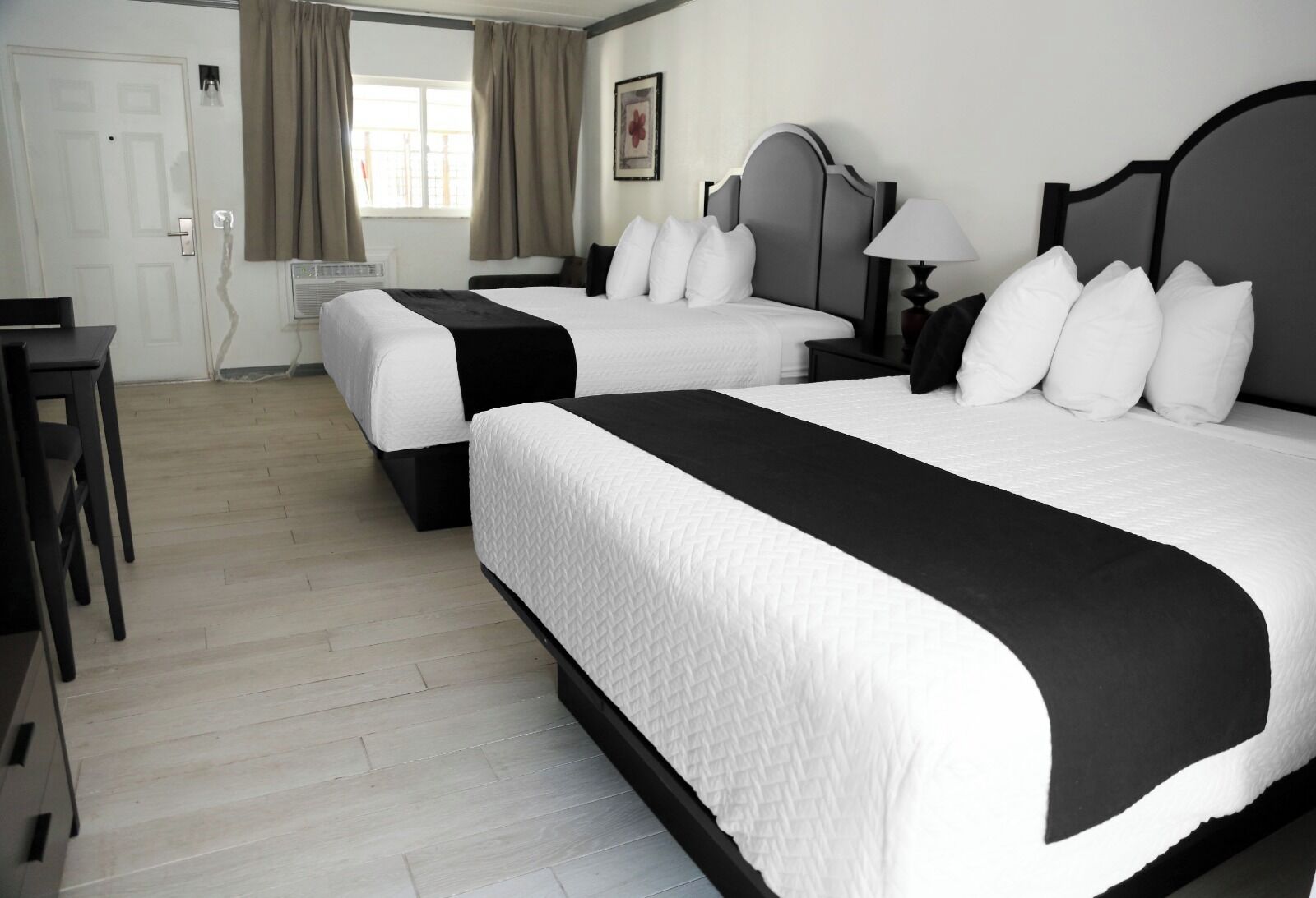 Een hotelkamer met twee bedden, een bureau en een raam met gordijnen.