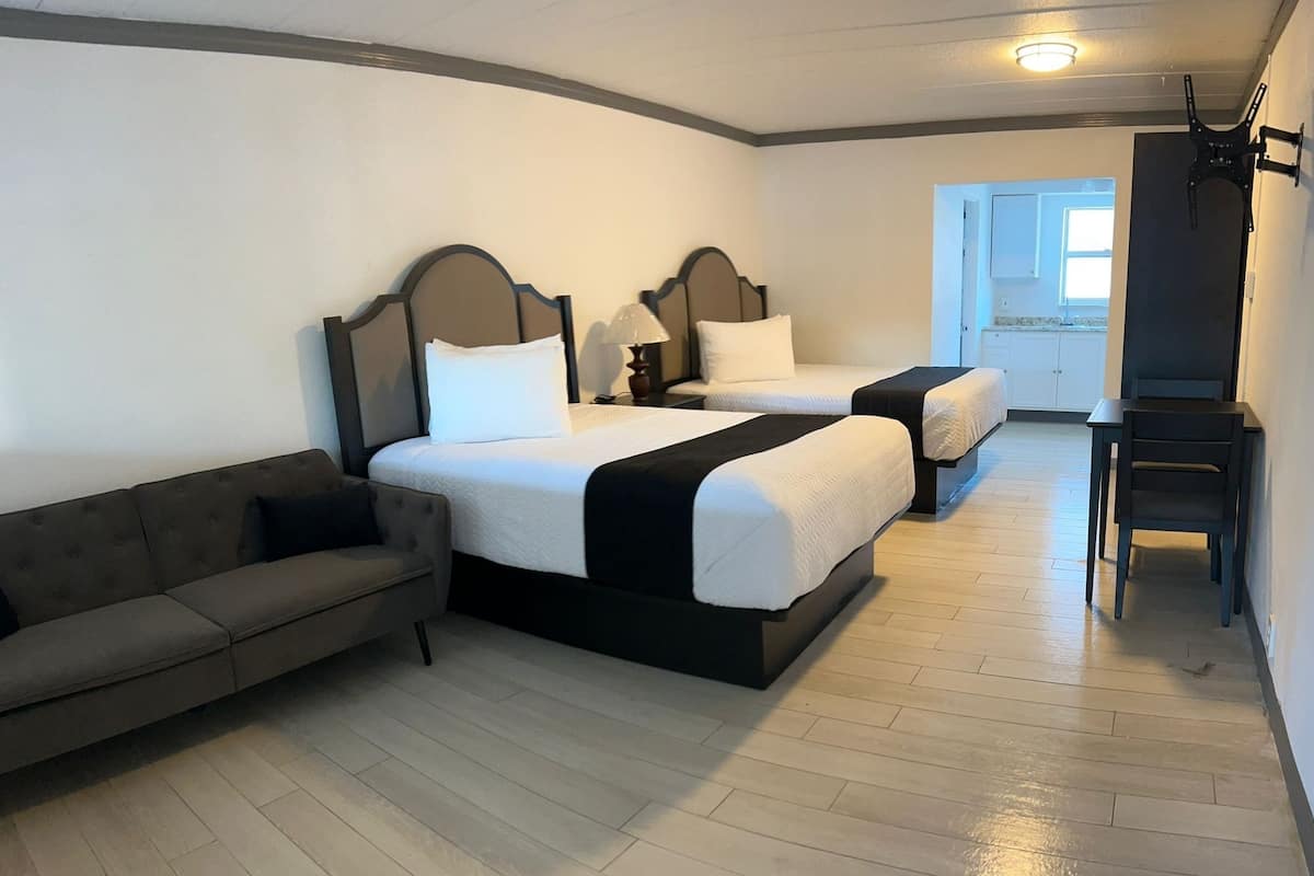 Ett hotellrum med två sängar, en soffa, ett skrivbord och en stol.