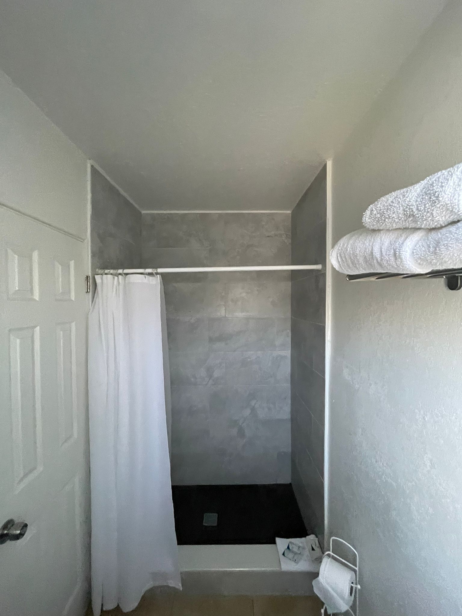 Un baño pequeño y estrecho con ducha, perchero y retrete.