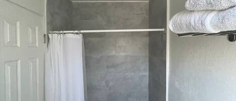Un baño pequeño y estrecho con ducha, perchero y retrete.