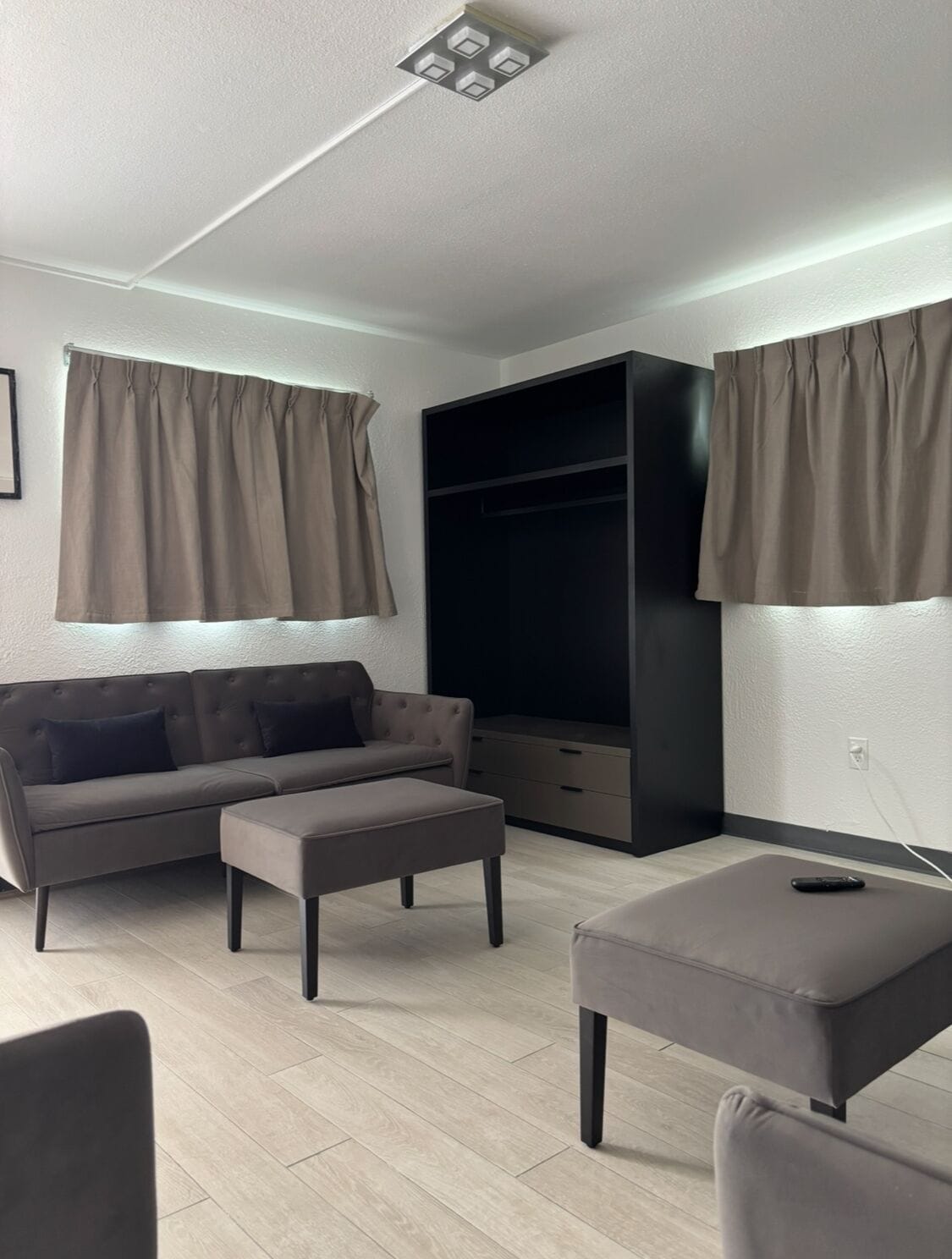 A modern living room with a sofa, ottoman, and a black entertainment unit.