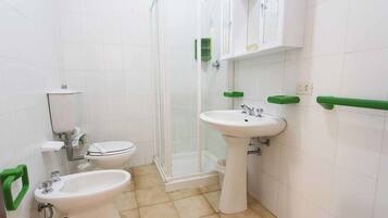 A bathroom with a toilet, bidet, sink, and shower.