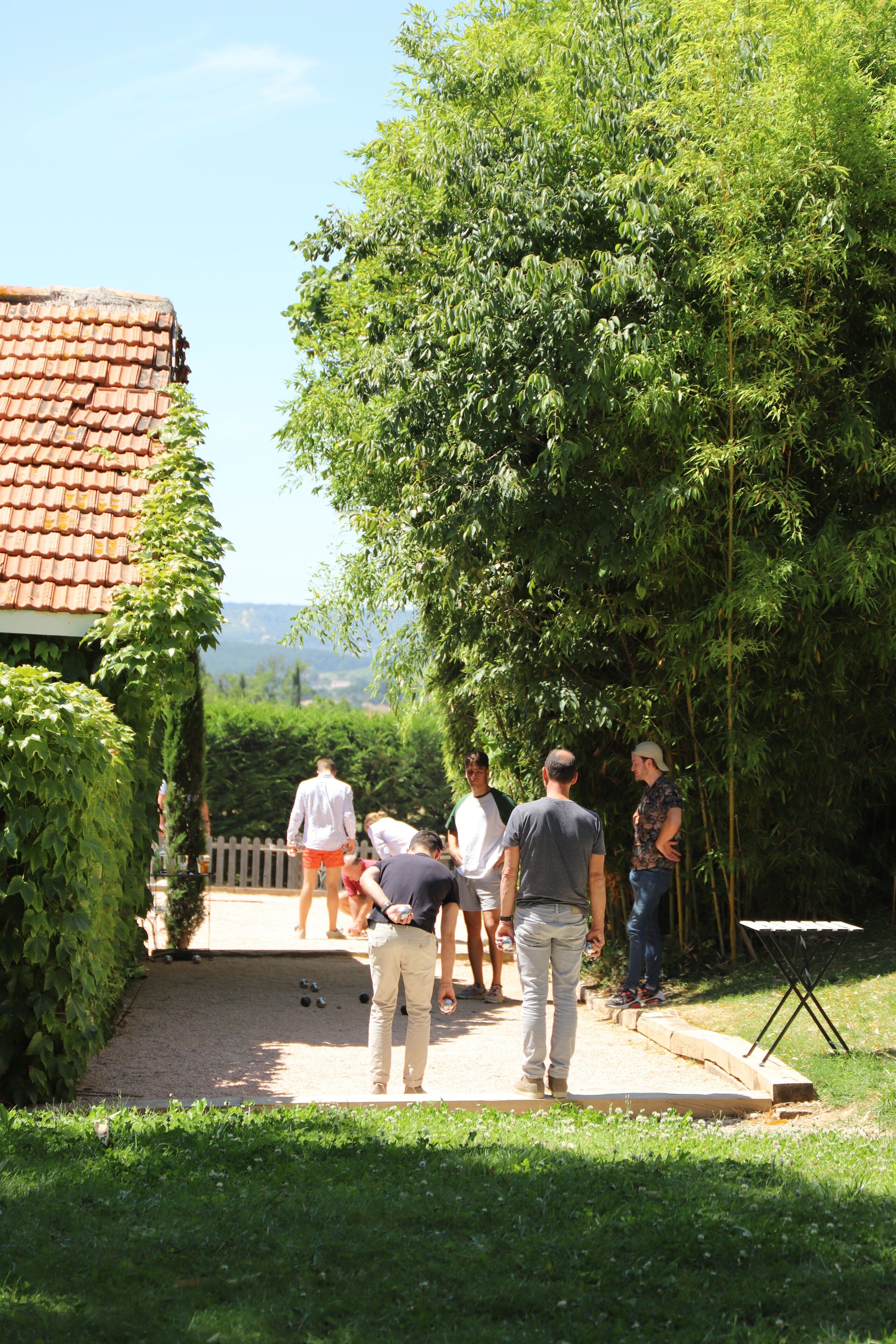 A group of people playing croquet in a garden with a house in the background.