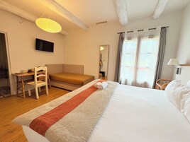 A hotel room with a bed, a desk, a chair, a television, and a window with curtains.