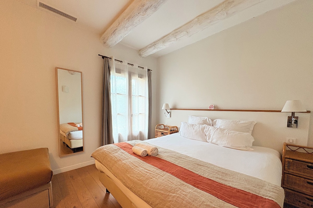 A hotel room with a large bed, a chair, a nightstand, and a mirror.
