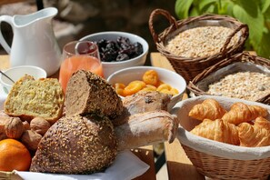 A variety of breads, pastries, and fruits on a wooden table. - Domaine Gao (Aix-en-Provence)