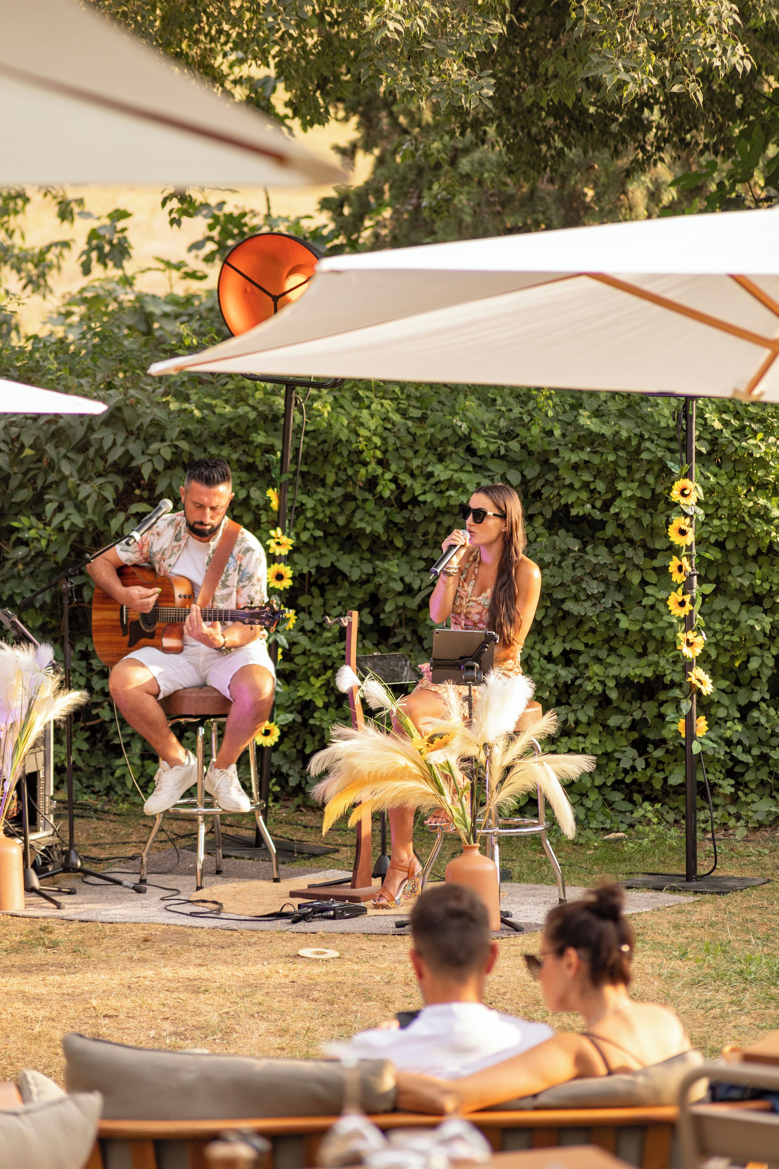 Evento al aire libre con un músico tocando la guitarra y una mujer cantando en un micrófono.