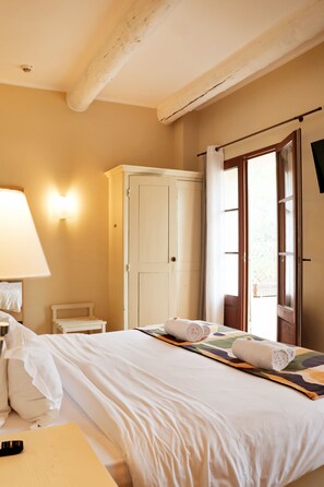 A hotel room with a bed, a wardrobe, a nightstand, a lamp, and a window with curtains. - Domaine Gao (Aix-en-Provence)