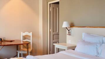 Una habitación de hotel con cama, escritorio, silla y lámpara.