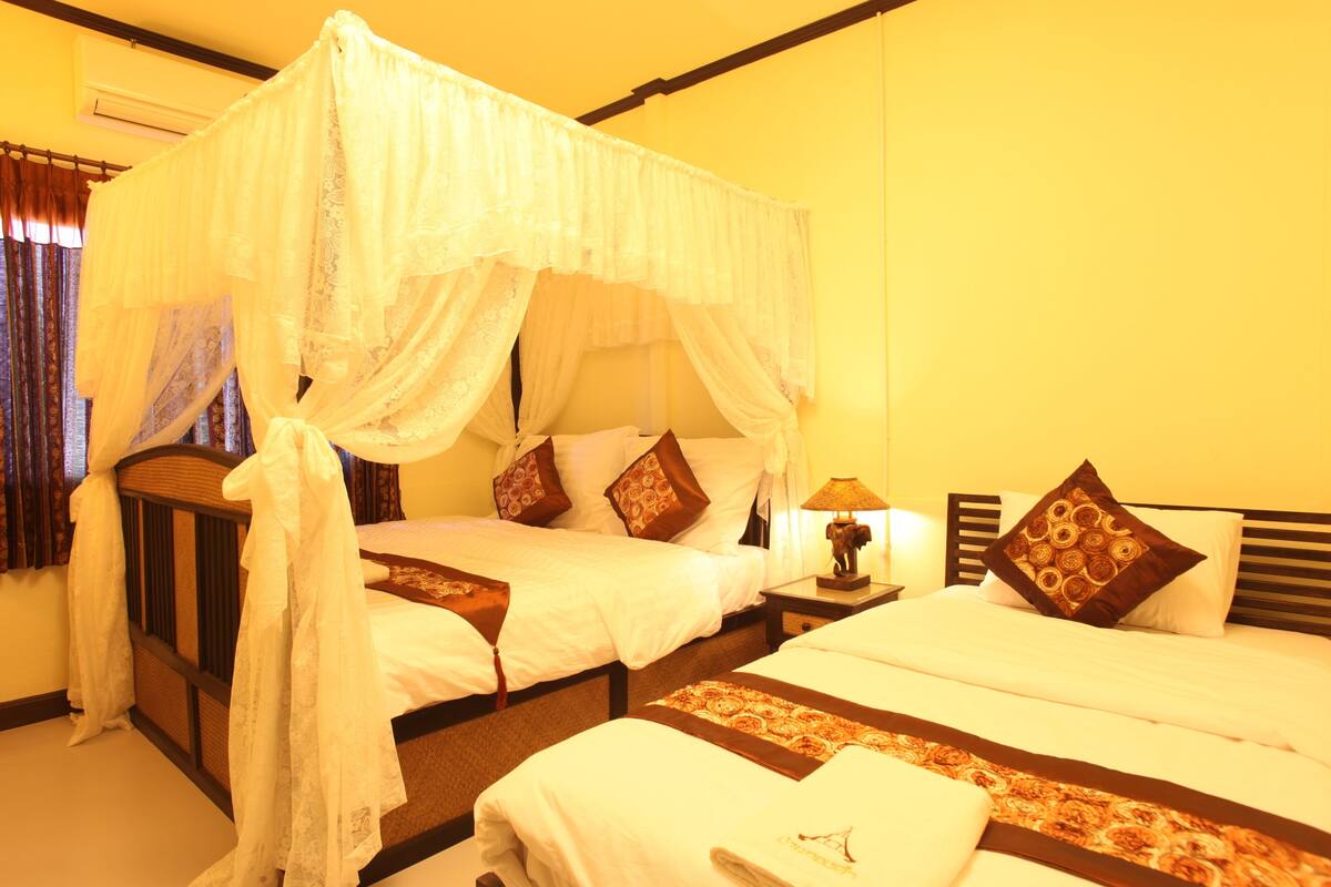 A room with two beds, each with a canopy, and a nightstand with a lamp.