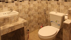 Une salle de bain avec un lavabo, des toilettes et une douche. Les murs sont recouverts d’un carrelage mural.