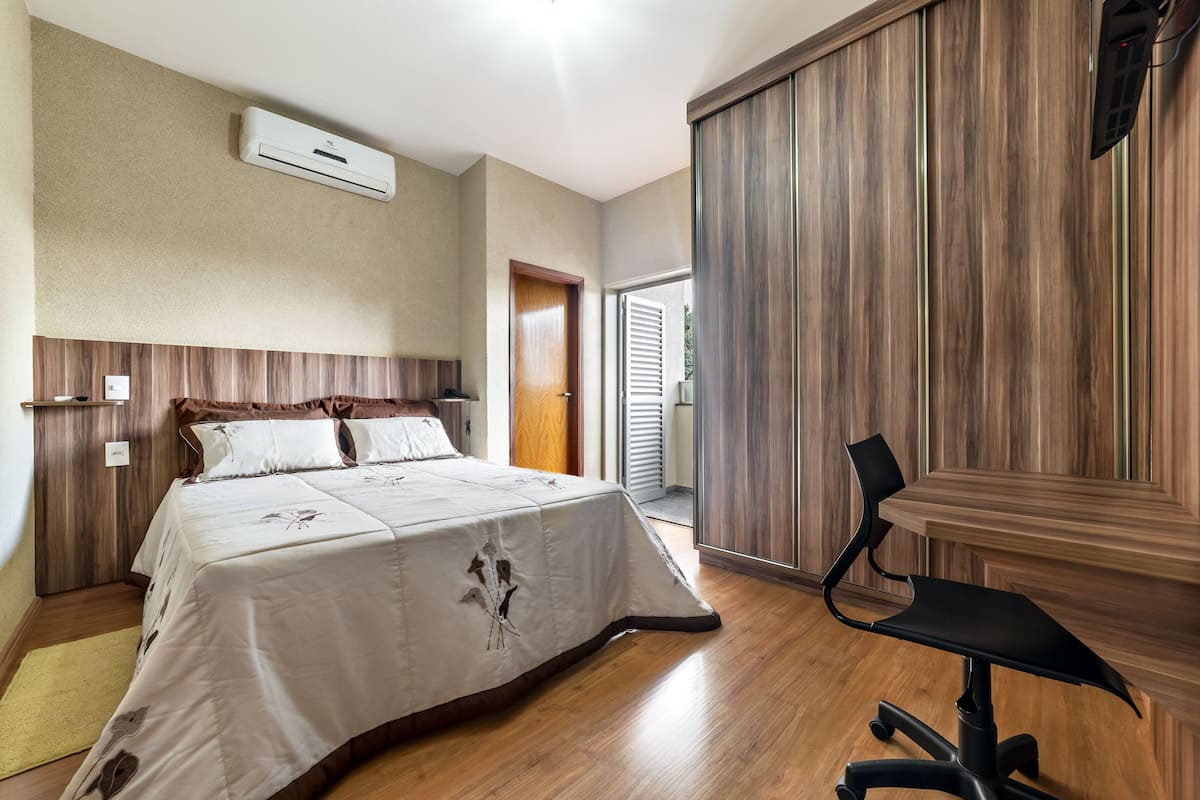 Un dormitorio con una cama, un escritorio y un equipo de aire acondicionado.