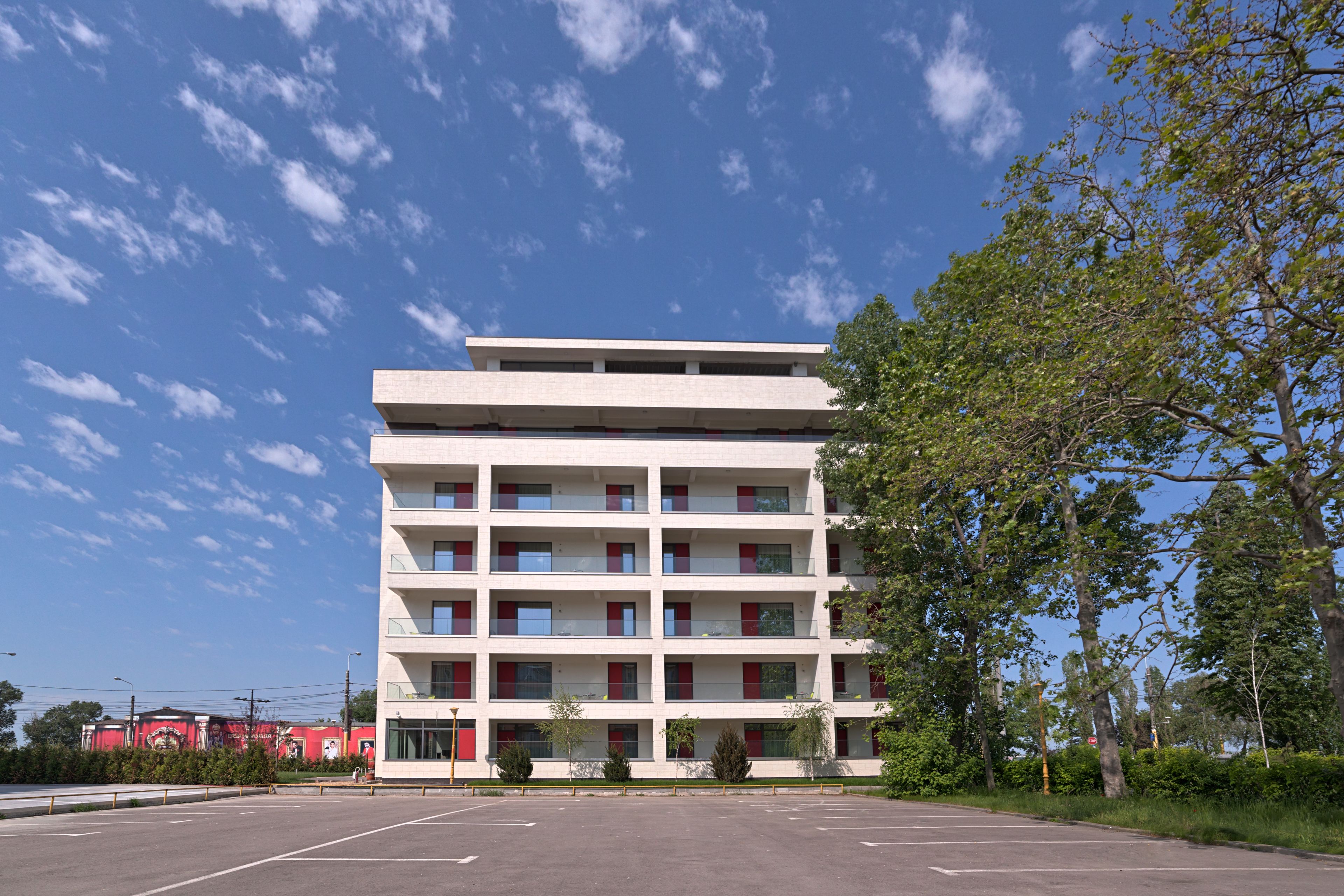 A multi-story building with a flat roof and a parking lot in front.