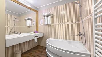 A modern bathroom with a large bathtub, a vanity with a mirror, and a shower area.