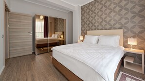 A modern hotel room with a large bed, a wardrobe, a bedside table with a lamp, and a patterned wall. - Tomis Garden Apartments (Constanta)