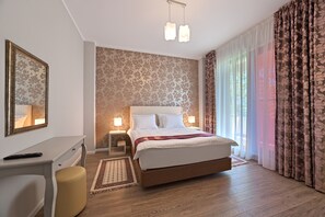 A hotel room with a large bed, bedside tables, a desk, a chair, and a mirror.