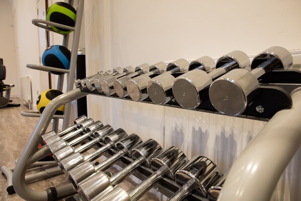 Une salle de sport avec plusieurs rangées d’haltères et de ballons d’exercice.