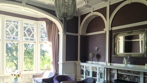 A room with a fireplace, bookshelves, and a large mirror.