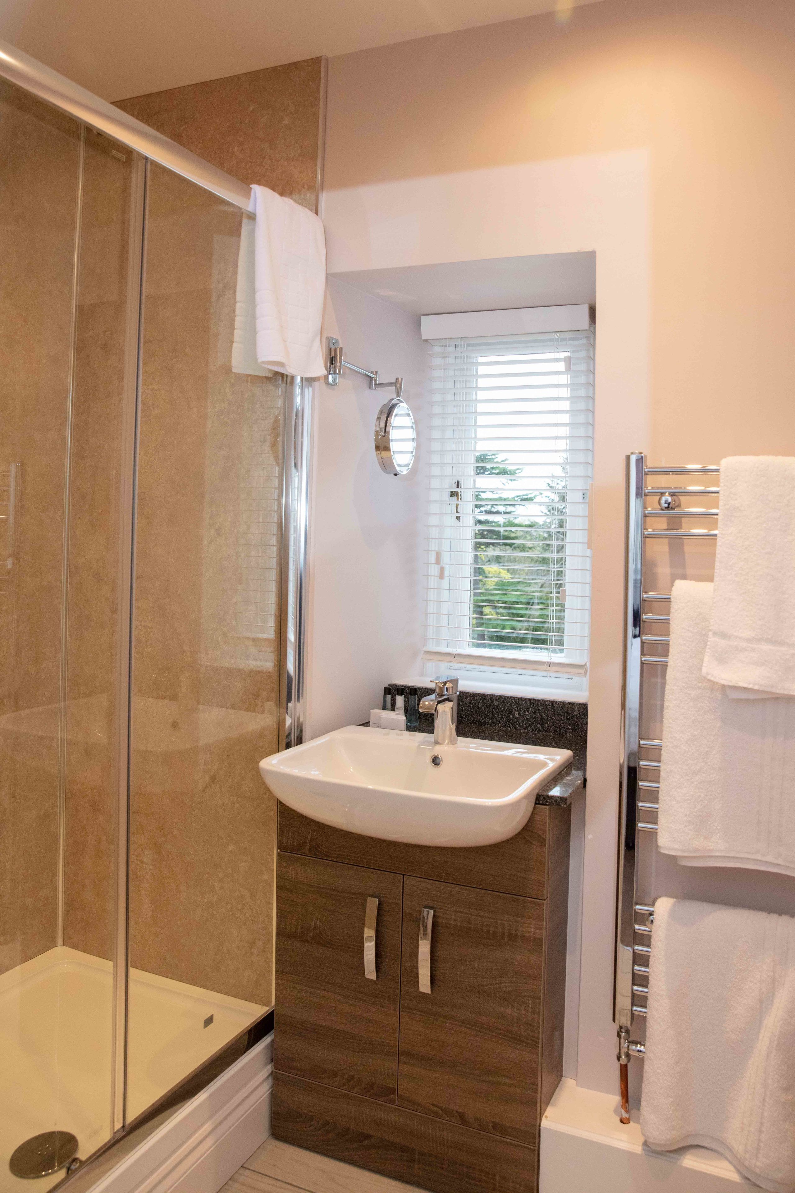Een moderne badkamer met een douche met glazen wand, een wit wastafelmeubel en een handdoekhouder.