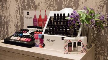 Eine Präsentation von Phénom Nagellackflaschen und -kartons auf einer Holztischplatte mit einer Blumenanordnung.