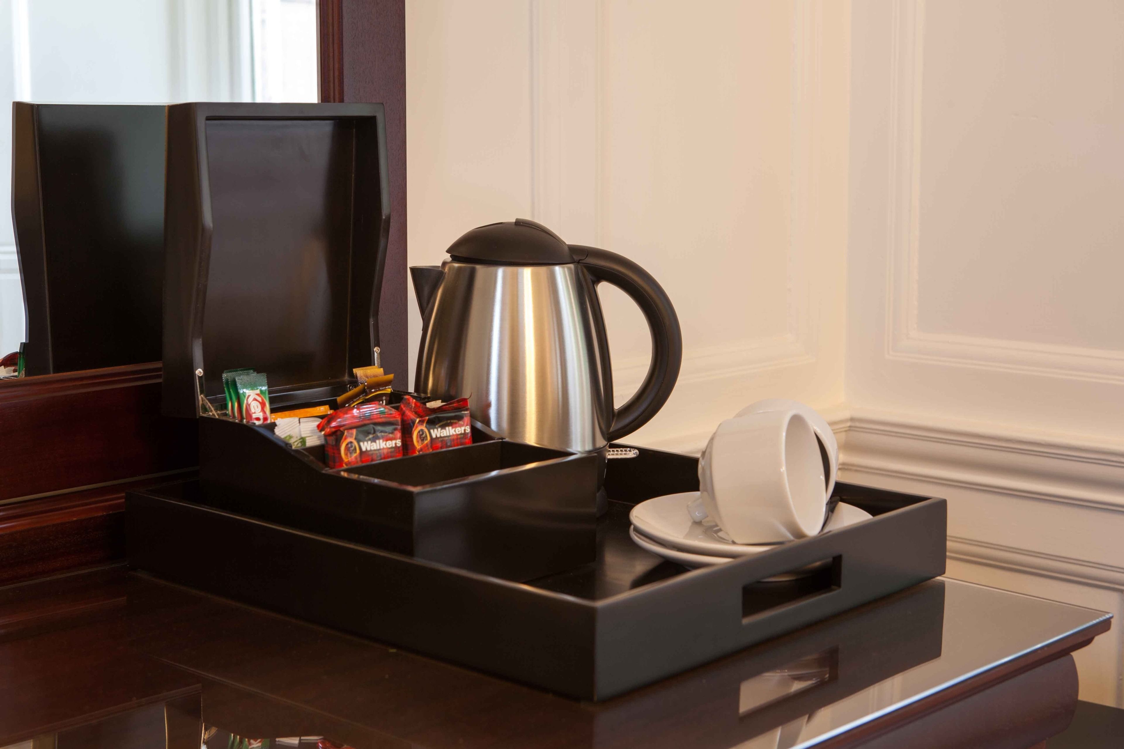 A coffee station with a kettle, cups, and snacks.