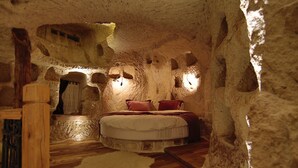 Une chambre à coucher qui ressemble à une grotte, avec un lit, des meubles en bois et des murs en pierre.