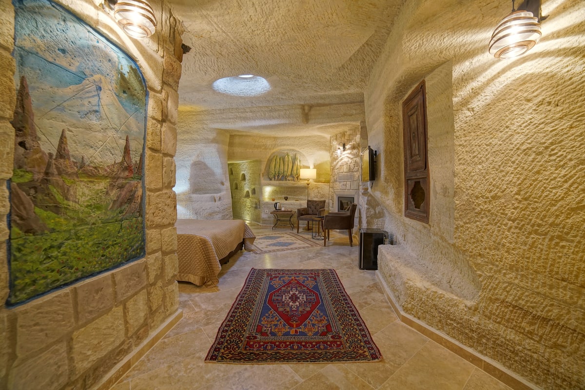 Une pièce aux murs de pierre, avec un lit, un bureau et une lampe.