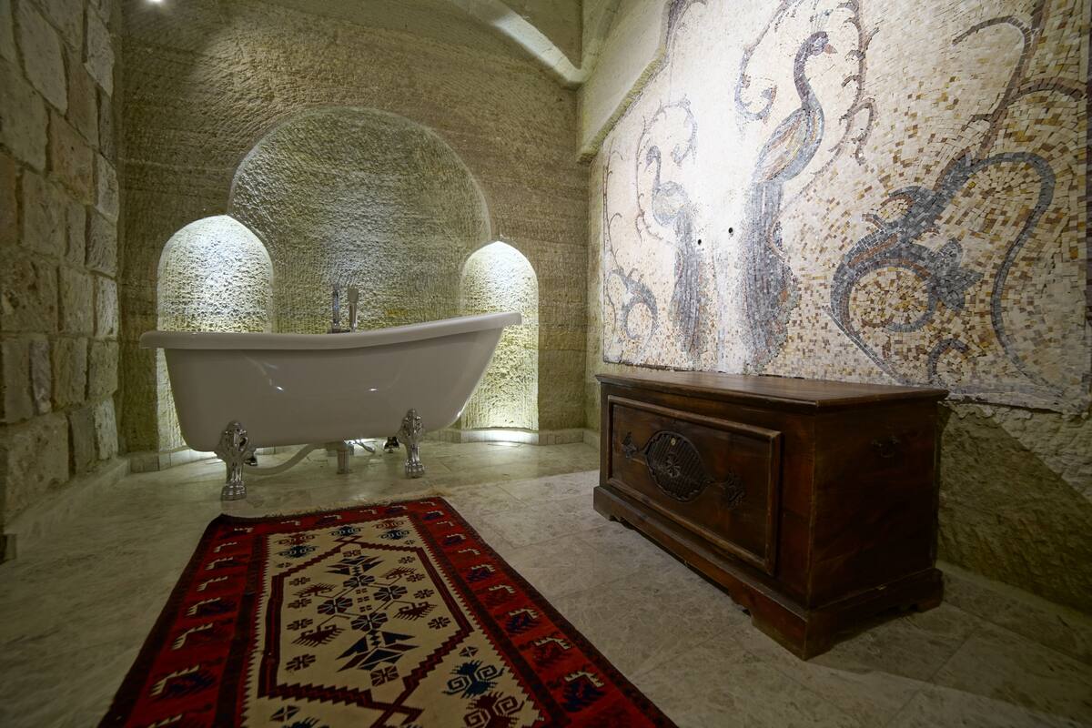Une pièce avec une baignoire sur pieds, une commode en bois et un tapis à motifs.