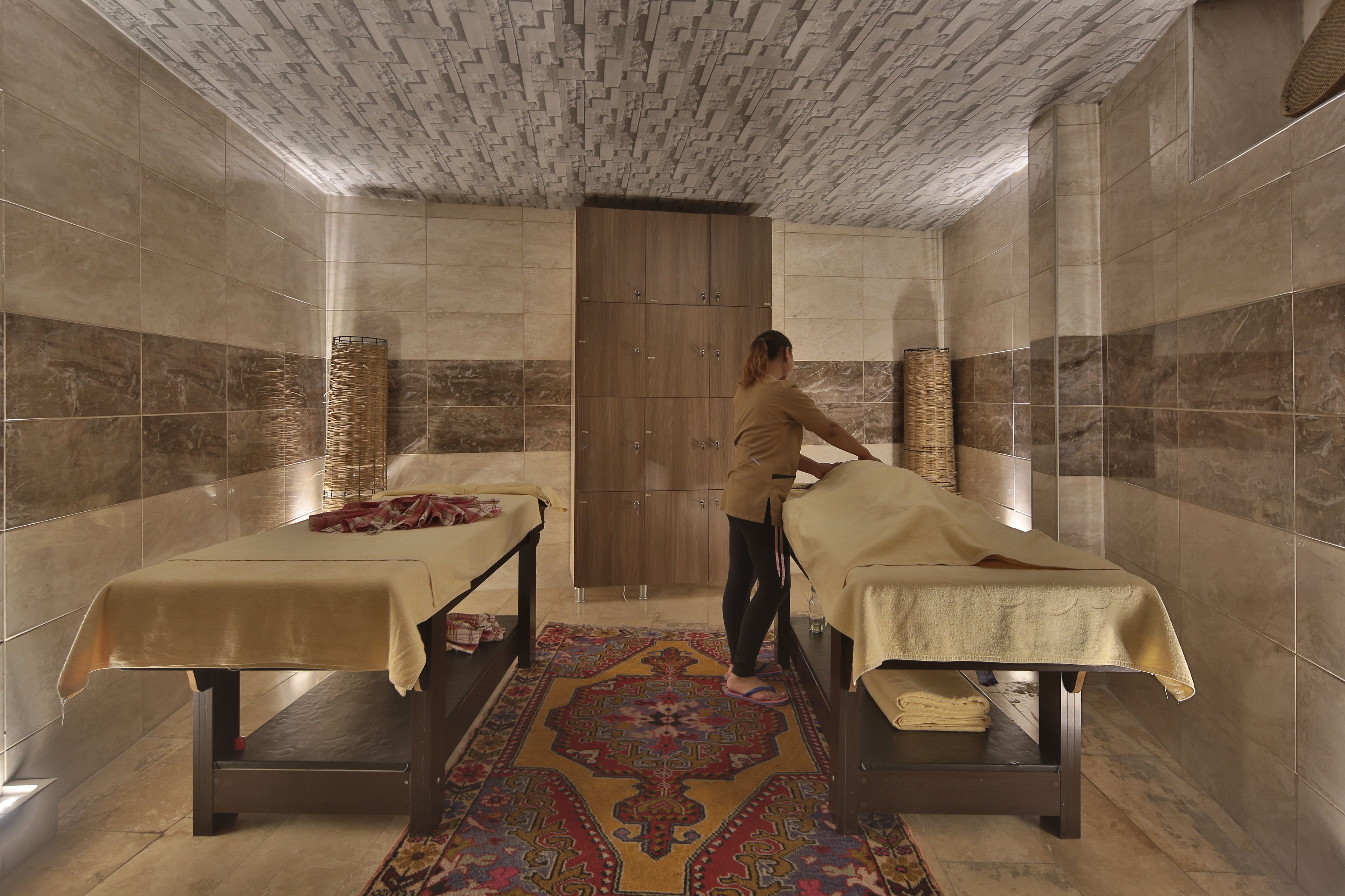 A room with two massage tables, a patterned rug, and a wooden door.