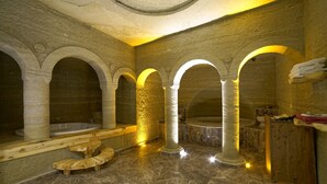 Un espace de bien-être doté d’arches en pierre, d’un banc en bois et d’une baignoire.