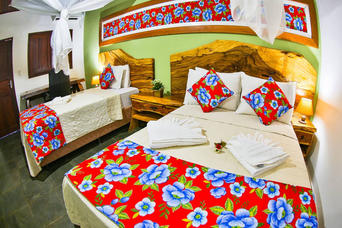 A hotel room with two beds, each with floral bedding, wooden headboards, and bedside tables with lamps.