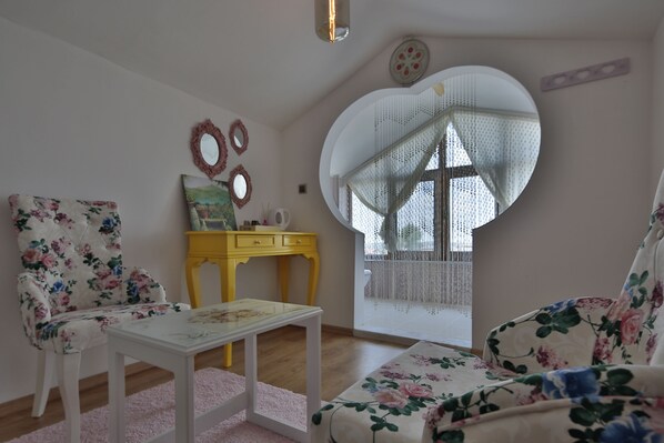 Un salón con tapicería floral, una mesa blanca y una mesita auxiliar amarilla.