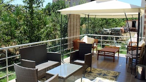 An outdoor patio with wicker furniture, a table, and a large umbrella providing shade. - Cozy Villa Cappadocia (Nevsehir)