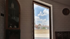 A room with a white brick wall, a wooden-framed mirror, and a view of a balcony with a clear sky. - Cozy Villa Cappadocia (Nevsehir)