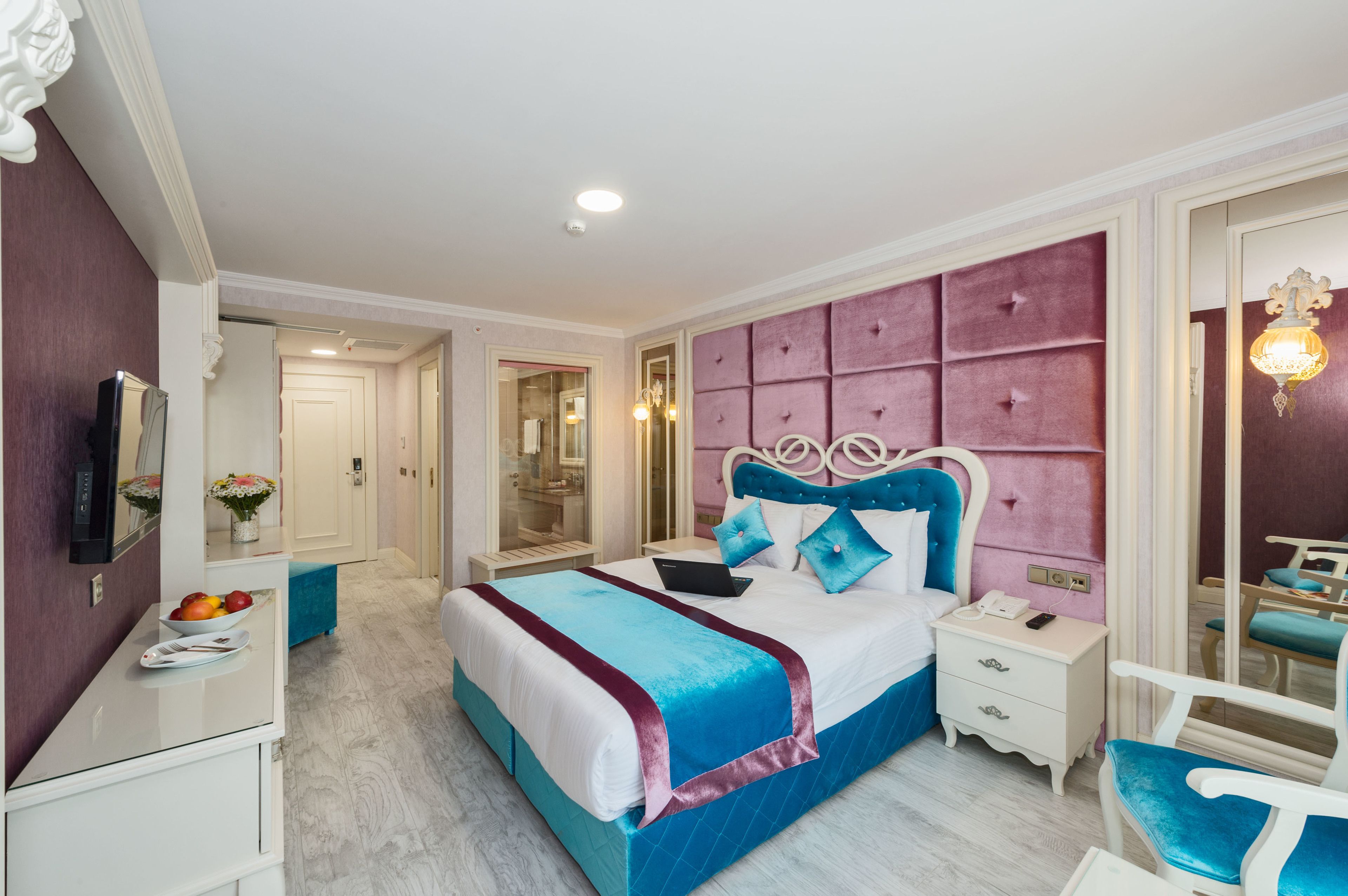 A bedroom with a bed, bedside tables, a mirror, a vanity, and a chair.