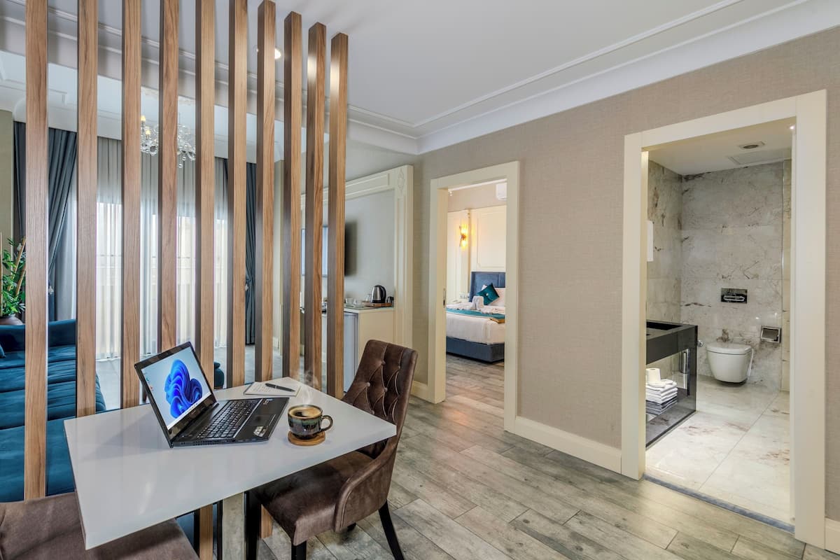 A modern hotel room with a dining area, a bed, a bathroom, and a view of the cityscape.
