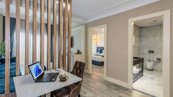 Quarto de hotel moderno com área de jantar, cama, banheiro e vista para a cidade.