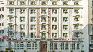 Edifício de vários andares do MARNAS HOTELS, com uma coluna decorativa central, varandas e uma entrada imponente.