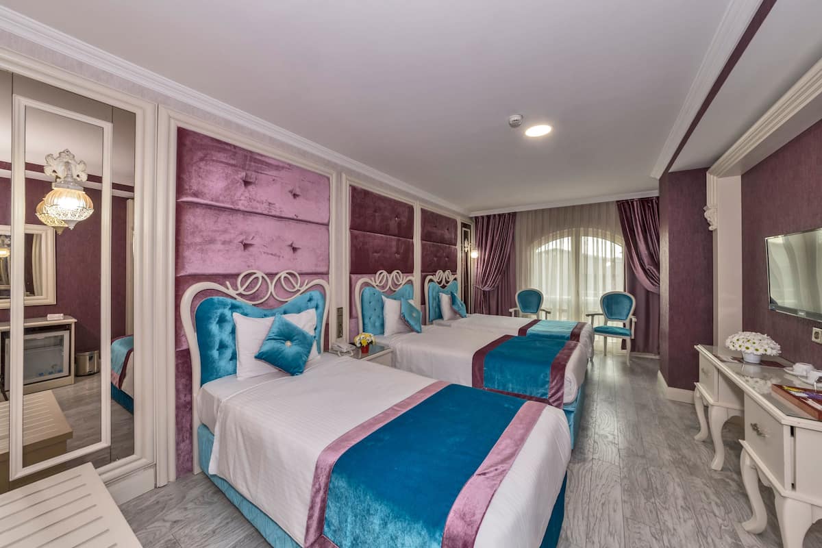 A hotel room with two beds, a vanity, and a desk.